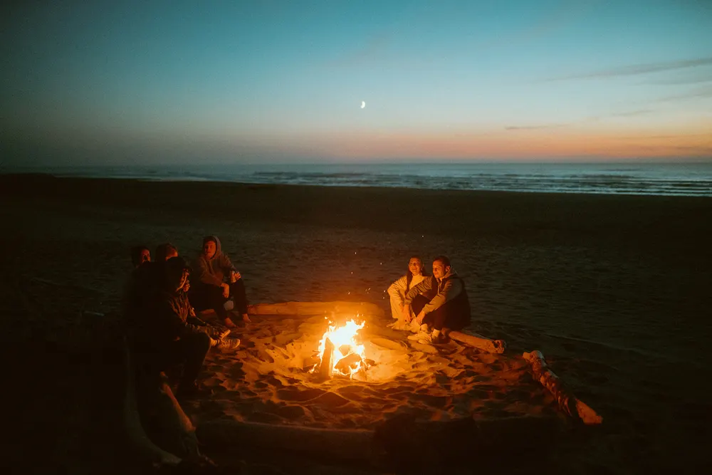 Friends gathered around the beach bonfire