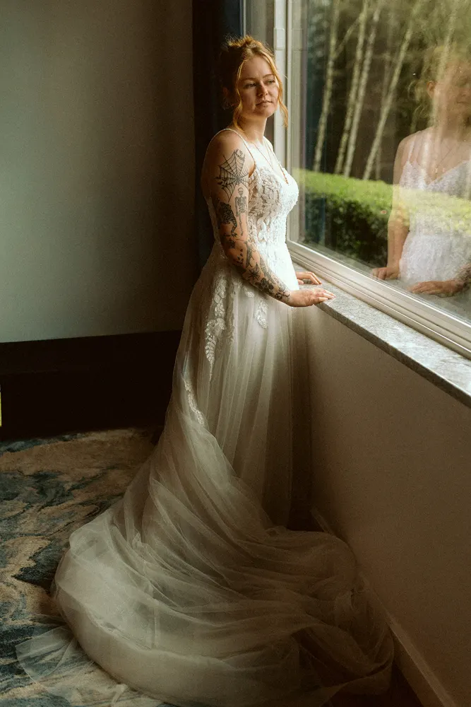 Alli in her wedding dress by the window